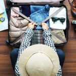 Overhead view of a traveler using travel hacks to efficiently pack a suitcase with essentials