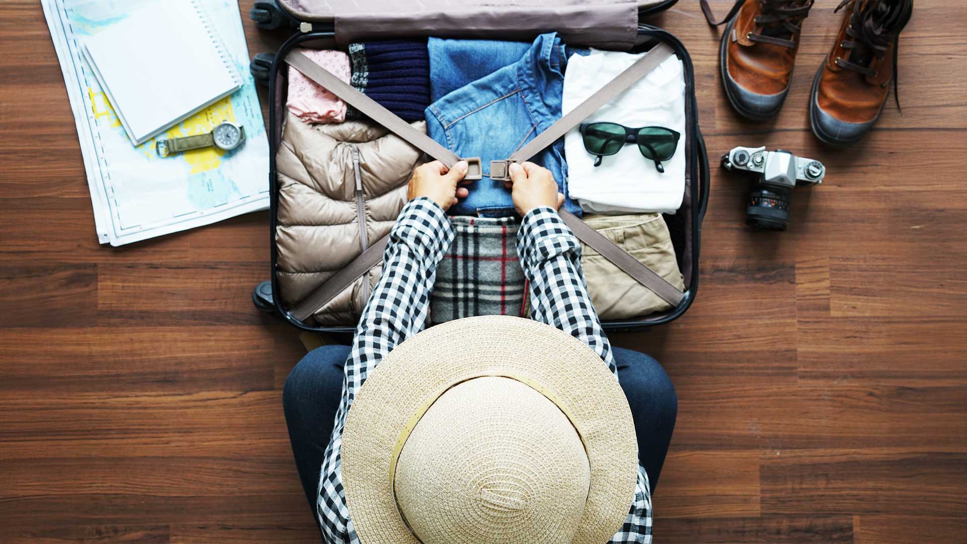 Overhead view of a traveler using travel hacks to efficiently pack a suitcase with essentials