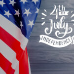 Close-up of the American flag with "4th of July Independence Day" text on a wooden background, symbolizing America's Independence Day.