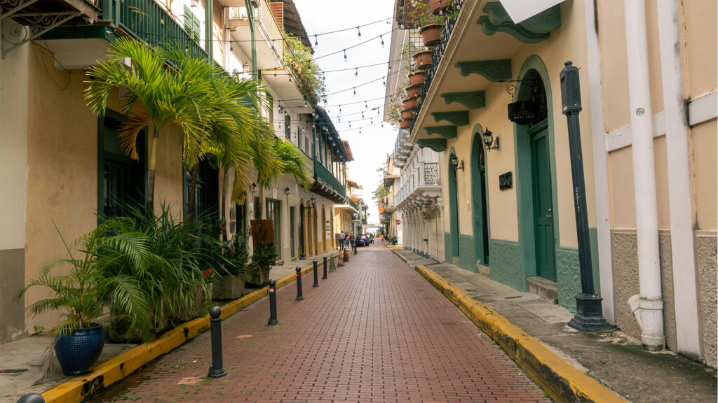 A charming colonial-style street located near Panama City Beach hotels, featuring vibrant buildings, tropical plants, and cozy walkways ideal for travelers.